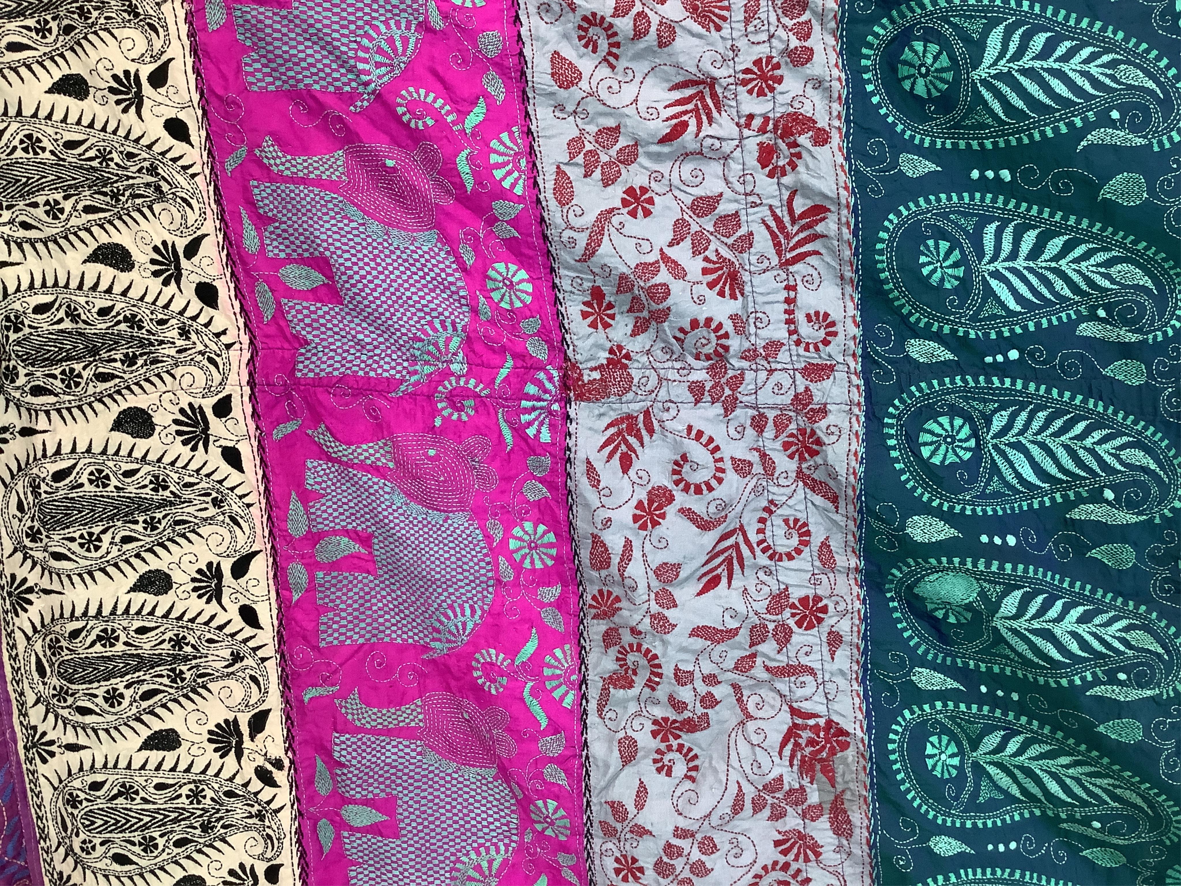 An Indian 20th century embroidered silk hanging, with decorative triangular tasselled edges. Worked in colourful silk stripes, with varying silk embroidered all over motifs. Bordered with colourful silk, beaded, tasselle